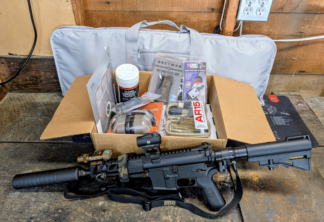 Four months of TacPack Plus gear including AR-15 parts, Vortex red dot, sling, rifle case, and range equipment